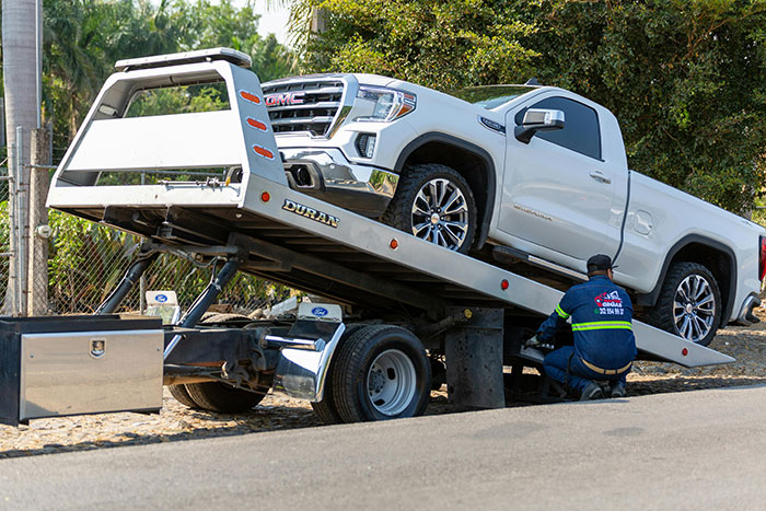 Tow truck loading a white pickup truck, highlighting a towing company scenario. Tow truck loading a white pickup truck, highlighting a towing company scenario.