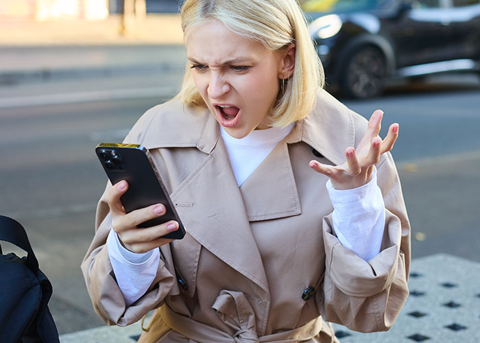 Woman looks surprised at her phone, expressing emotion during a solo trip endeavor. Woman looks surprised at her phone, expressing emotion during a solo trip endeavor.