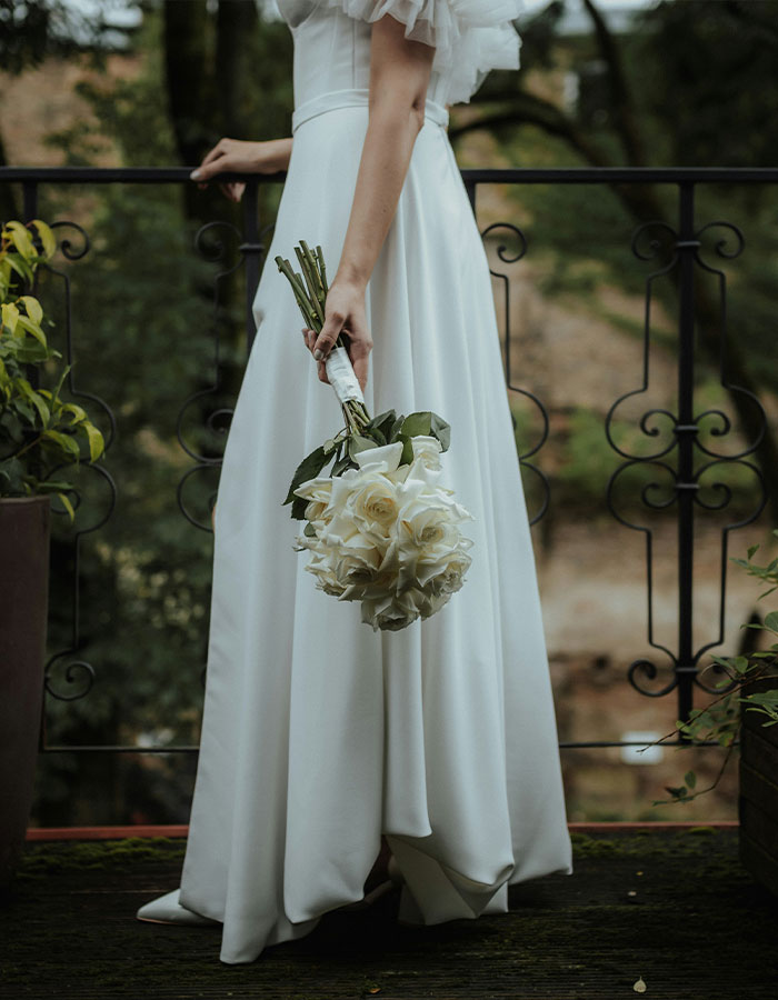 Bride holding bouquet, standing on balcony, evokes wedding day emotions and reflections. Bride holding bouquet, standing on balcony, evokes wedding day emotions and reflections.