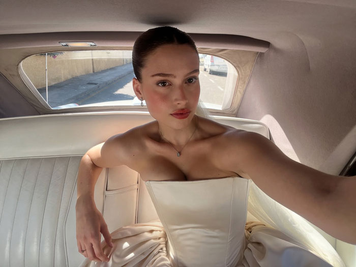 Bride in a dramatic wedding dress with veil, seated in a car, creating a fashion statement. Bride in a dramatic wedding dress with veil, seated in a car, creating a fashion statement.