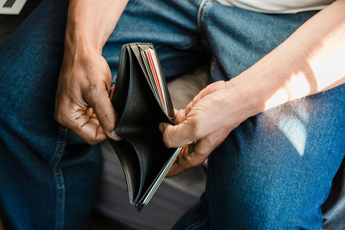 Man holding an empty wallet, concerned about maintaining an expensive gift. Man holding an empty wallet, concerned about maintaining an expensive gift.