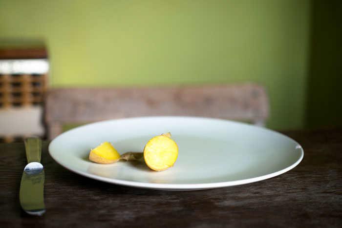 Plate with sliced ginger on a wooden table, emphasizing simplicity and minimalism. Plate with sliced ginger on a wooden table, emphasizing simplicity and minimalism.
