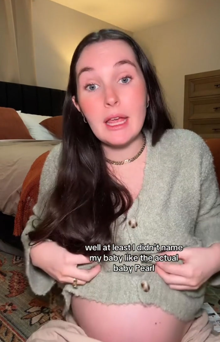 Pregnant woman discussing the name Pearl for her cousin's baby, wearing a cozy sweater in a warmly-lit room. Pregnant woman discussing the name Pearl for her cousin's baby, wearing a cozy sweater in a warmly-lit room.