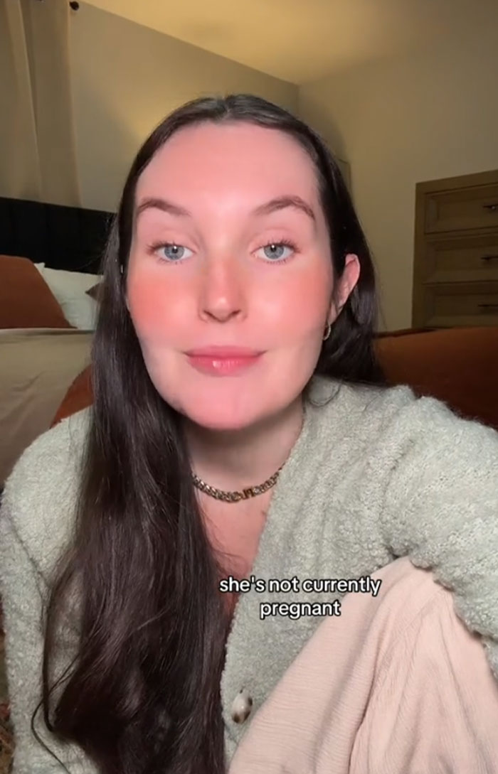 Woman discusses "accidentally" naming dog Pearl in cozy room setting, wearing a light sweater. Woman discusses "accidentally" naming dog Pearl in cozy room setting, wearing a light sweater.