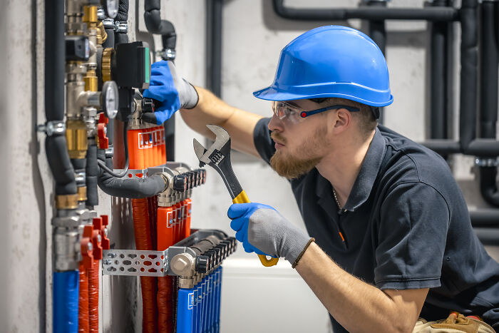 Engineer in blue helmet working on machinery, holding a wrench in an industrial setting. Engineer in blue helmet working on machinery, holding a wrench in an industrial setting.