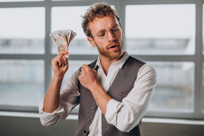 Man holding euros confidently in an office, symbolizing lottery win, reflecting on his engineer work commitment. Man holding euros confidently in an office, symbolizing lottery win, reflecting on his engineer work commitment.
