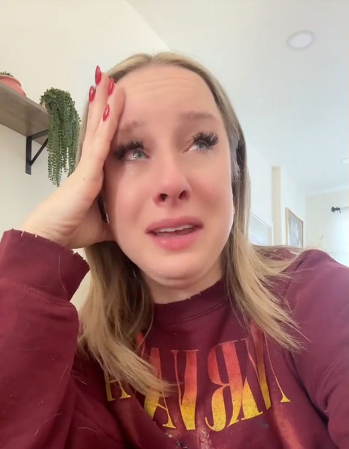 Person reacting emotionally to US TikTok ban news, wearing a red sweater indoors. Person reacting emotionally to US TikTok ban news, wearing a red sweater indoors.
