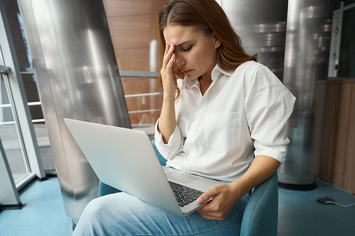 Woman looking frustrated at laptop, experiencing discomfort in group chat conversation. Woman looking frustrated at laptop, experiencing discomfort in group chat conversation.