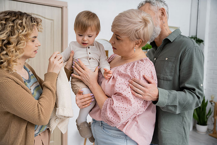 Family gathering around a baby, showing mixed emotions after hearing the chosen name. Family gathering around a baby, showing mixed emotions after hearing the chosen name.