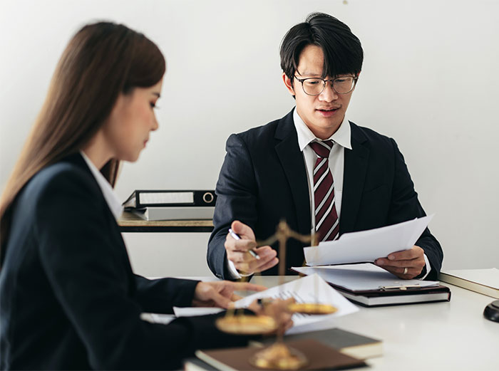 Two professionals discussing inheritance documents in an office setting. Two professionals discussing inheritance documents in an office setting.