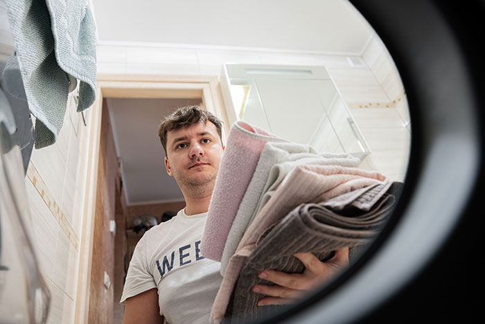 Man doing laundry at home, viewed from inside a washing machine. Man doing laundry at home, viewed from inside a washing machine.