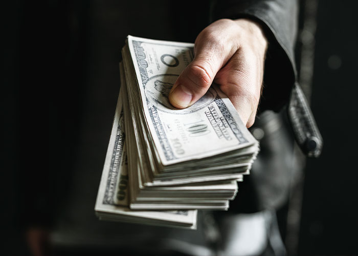 Person holding a stack of cash, symbolizing sudden inheritance and true colors revealed. Person holding a stack of cash, symbolizing sudden inheritance and true colors revealed.
