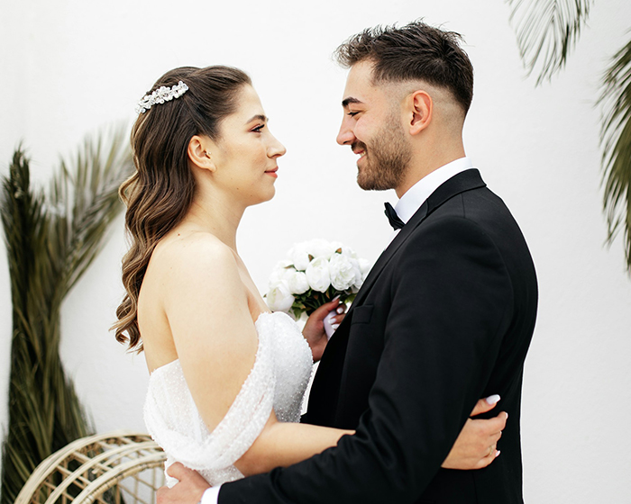 A bride and groom stand close, gazing at each other, surrounded by lush greenery, in a moment of joy and connection. A bride and groom stand close, gazing at each other, surrounded by lush greenery, in a moment of joy and connection.