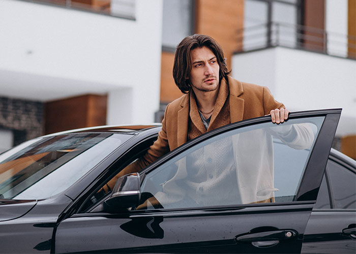 Man in a brown coat sitting in a black car during a yard sale event with police intervention. Man in a brown coat sitting in a black car during a yard sale event with police intervention.