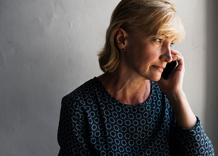 Woman in patterned blouse on phone, looking thoughtful about rent discussions. Woman in patterned blouse on phone, looking thoughtful about rent discussions.