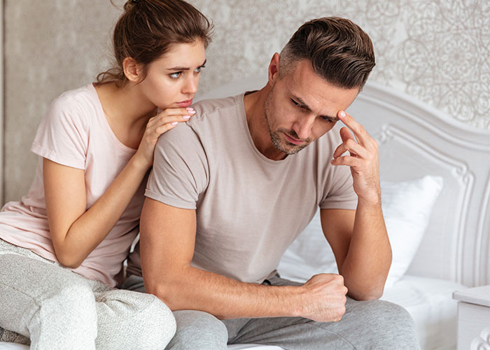 Wife comforts husband on bed, both wearing casual clothes, highlighting an emotional moment. Wife comforts husband on bed, both wearing casual clothes, highlighting an emotional moment.