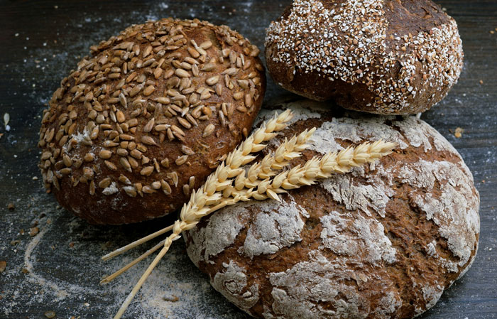 Assorted artisan breads topped with seeds and grains, showcasing rich people’s taste beyond reality.