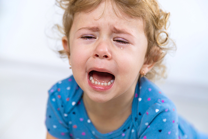 A toddler crying with tears, expressing a tantrum in a blue polka dot outfit. A toddler crying with tears, expressing a tantrum in a blue polka dot outfit.