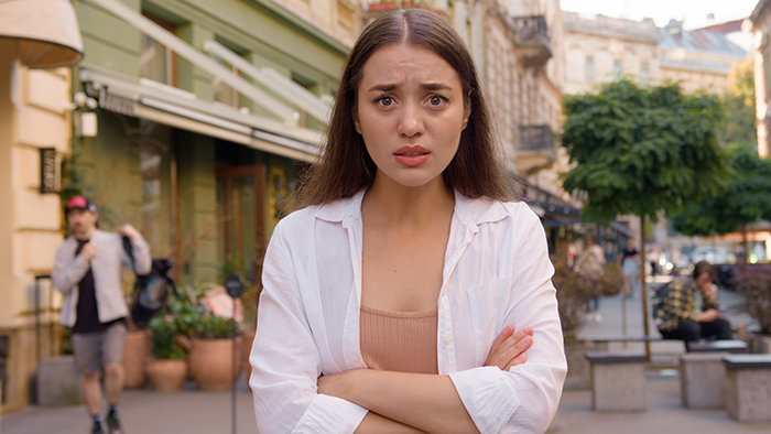 Young woman on city street, looking concerned, crossing her arms, related to dad’s girlfriend parenting dynamic. Young woman on city street, looking concerned, crossing her arms, related to dad’s girlfriend parenting dynamic.