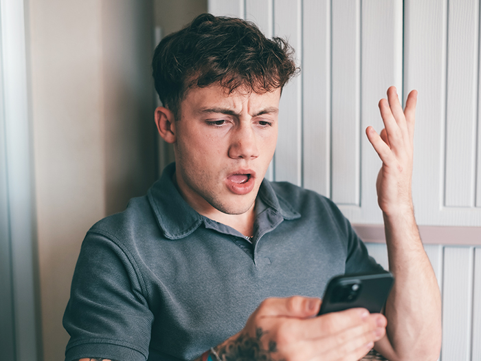 Teen looking surprised at phone, referencing fake account creation to influence religious parents' views on brother's sexuality. Teen looking surprised at phone, referencing fake account creation to influence religious parents' views on brother's sexuality.