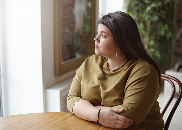Person in a contemplative mood, sitting by a window.