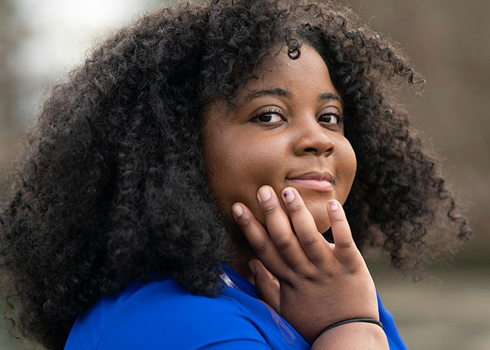 Person in a blue shirt smiling gently, representing experiences of being overweight.