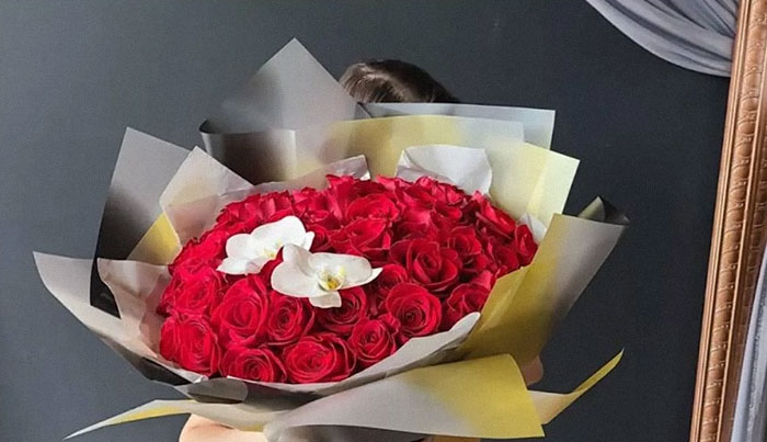 Bouquet with red roses and white orchids held in front of a dark background, related to bad reviews and business. Bouquet with red roses and white orchids held in front of a dark background, related to bad reviews and business.