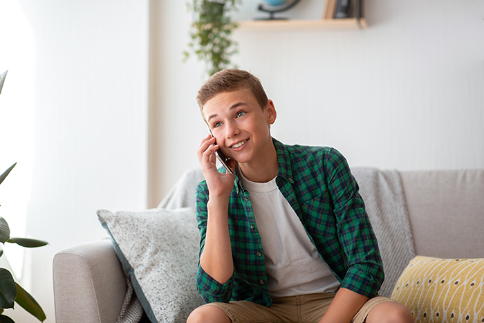 Teen sitting on a couch, talking on the phone, wearing a green plaid shirt, representing a story about proving someone isn't gay. Teen sitting on a couch, talking on the phone, wearing a green plaid shirt, representing a story about proving someone isn't gay.