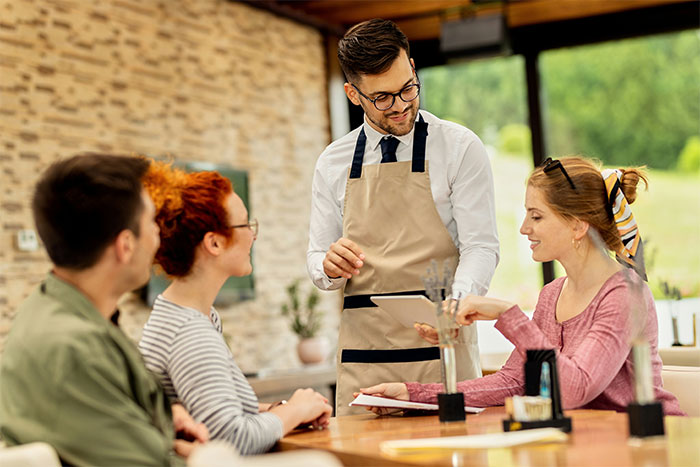 People sitting at a restaurant table, a waiter taking their order, meal payment discussed among friends. People sitting at a restaurant table, a waiter taking their order, meal payment discussed among friends.