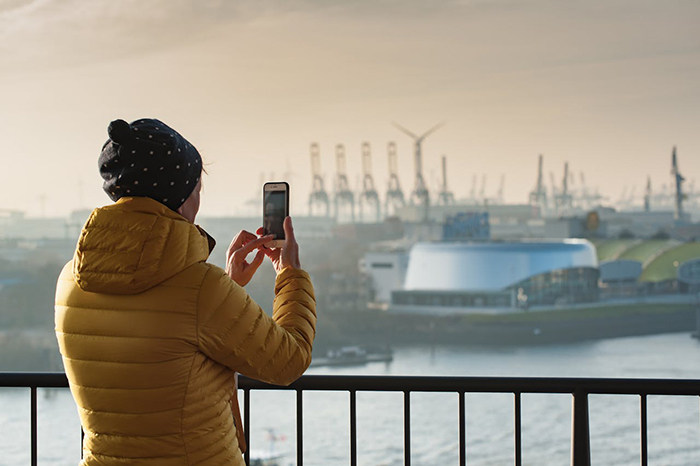 German woman in yellow coat taking photo of a harbor, sharing cultural insights. German woman in yellow coat taking photo of a harbor, sharing cultural insights.