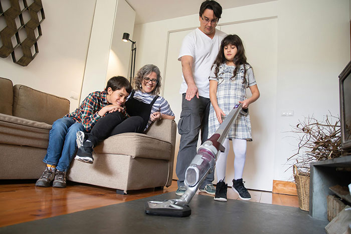 Family in living room as a child vacuums, highlighting the topic of parents and chores without payment. Family in living room as a child vacuums, highlighting the topic of parents and chores without payment.