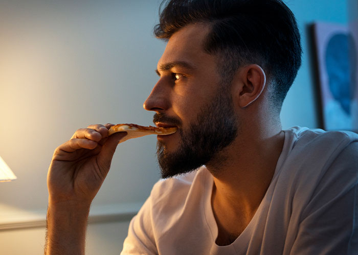 Man eating pizza, reflecting after a husband's birthday meltdown. Man eating pizza, reflecting after a husband's birthday meltdown.