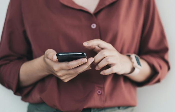 Woman in a red shirt using a smartphone, with a focus on hands and a smartwatch for communication. Woman in a red shirt using a smartphone, with a focus on hands and a smartwatch for communication.