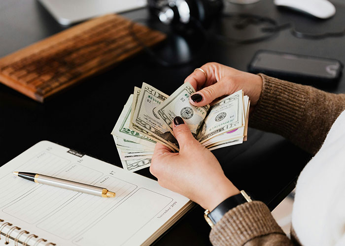Person counting money with a notebook and pen, highlighting affordability concerns for young parents. Person counting money with a notebook and pen, highlighting affordability concerns for young parents.