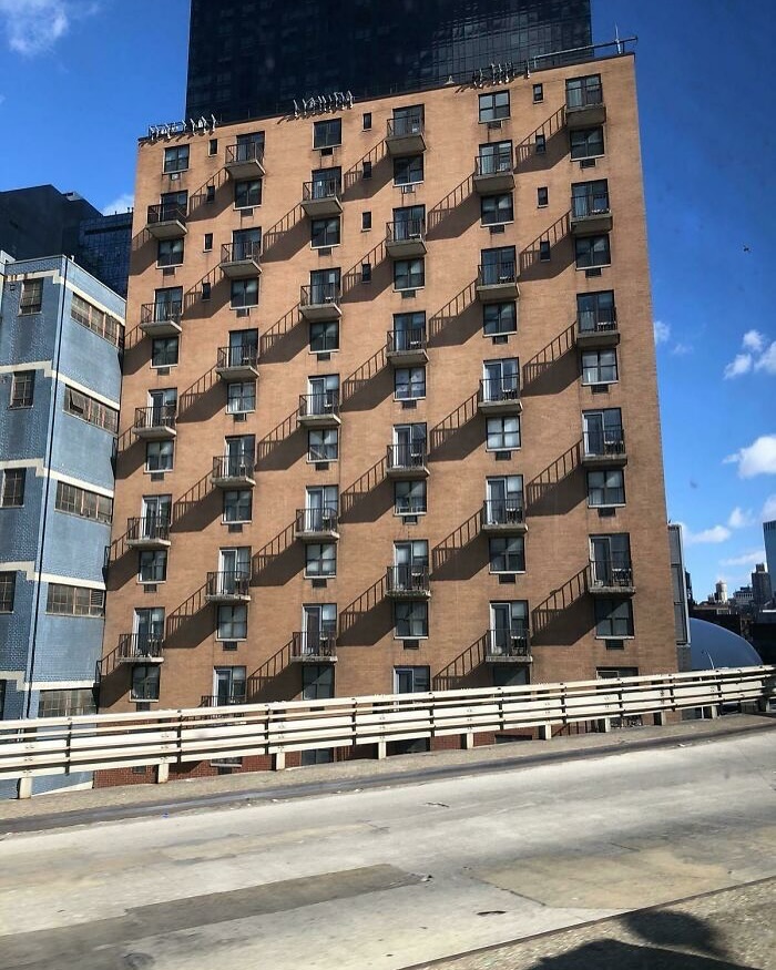 Building facade with diagonal shadows from balconies, showcasing interesting architectural design. 