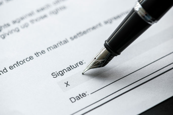 A pen signing divorce papers, highlighting unexpected consequences of a woman's joke. A pen signing divorce papers, highlighting unexpected consequences of a woman's joke.