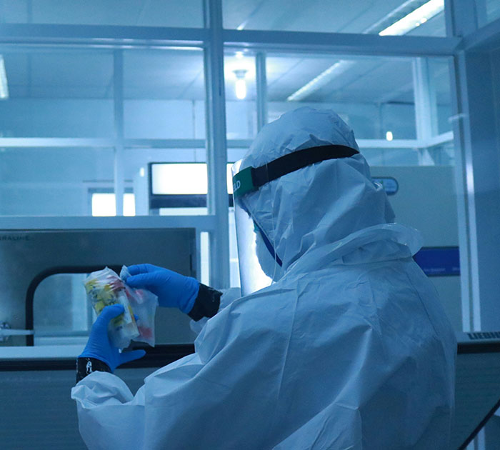 Scientist in protective gear examining specimen in lab related to Covid vaccines and syndrome research. Scientist in protective gear examining specimen in lab related to Covid vaccines and syndrome research.
