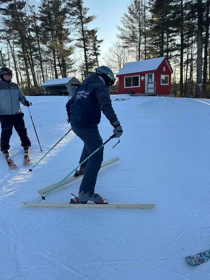 Person skiing on homemade wooden skis in a snowy area showcasing redneck engineer ingenuity and creativity outdoors.