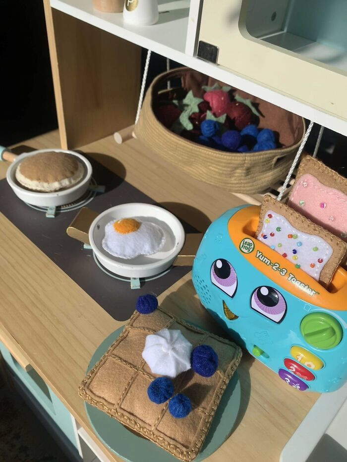 DIY play kitchen with felt food, including a waffle with berries, fried egg, and a toy toaster.