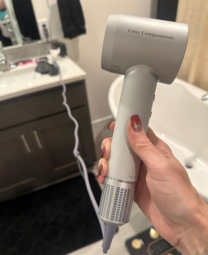 Hand holding a hair dryer in a bathroom, highlighting things worth spending money on.