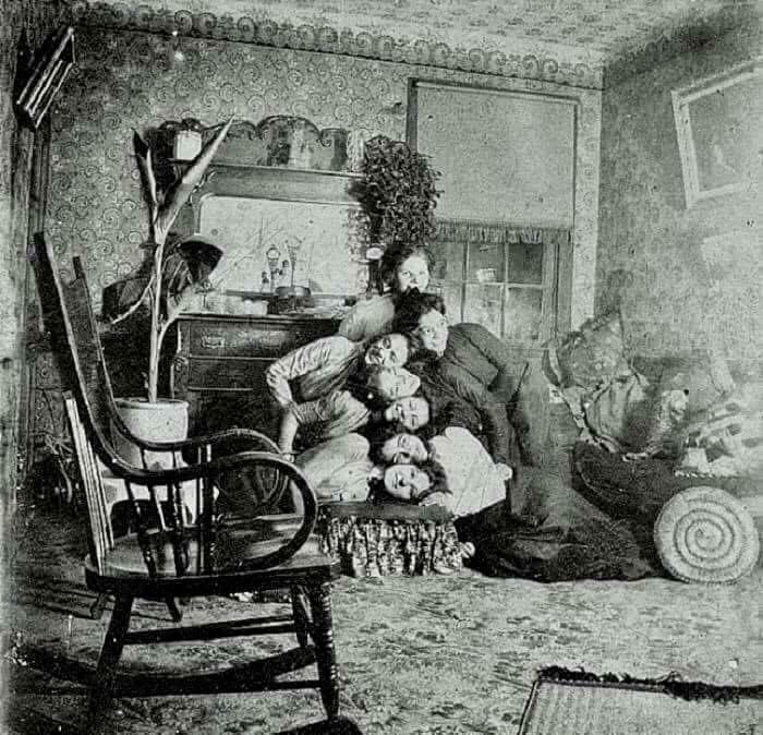 Group of people posing playfully in a vintage room, showcasing a fascinating old image not seen in history class.