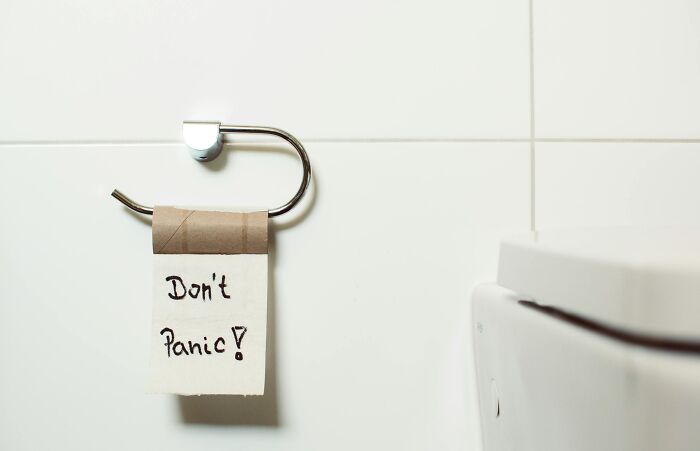 Empty toilet paper roll with "Don't Panic!" sign, a humorous office joke.