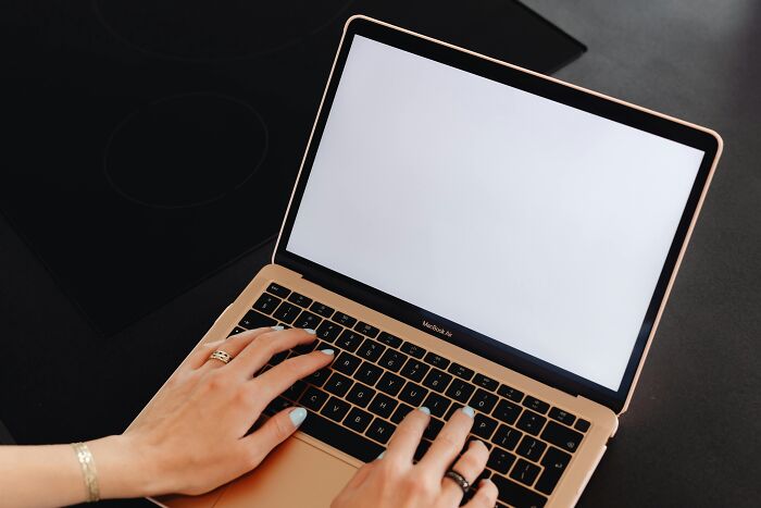 Person typing on a blank laptop screen, possibly brainstorming jokes about office settings.