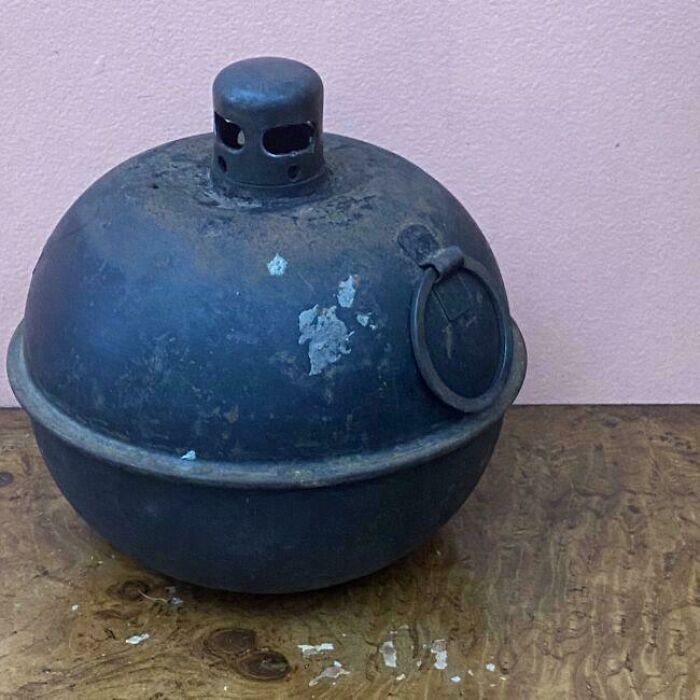 A vintage black metal object with a handle and lid, evoking nostalgia.