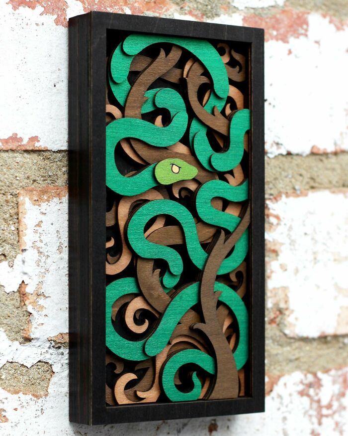 Colorful DIY project featuring intricate green and brown woodcut artwork in a black frame against a brick wall.