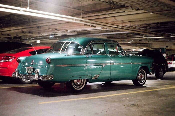 A vintage green car parked in an underground garage, showcasing classic design and elegance.
