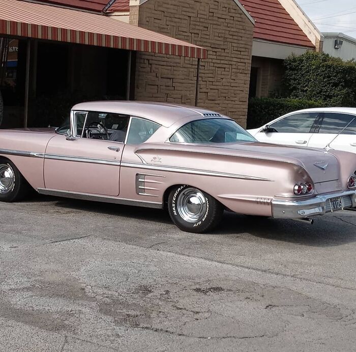 Pink fascinating vintage car parked in front of a building, showcasing classic design elements.