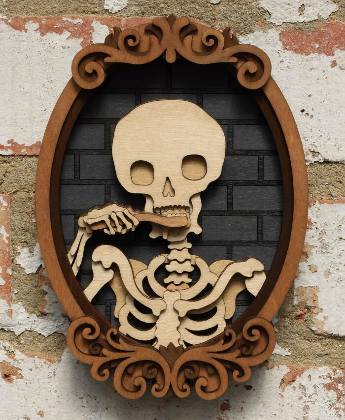 Skeleton DIY project wall art made of wood, brushing its teeth in a decorative frame, on a textured background.