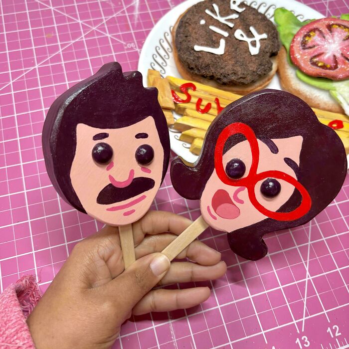 DIY projects featuring colorful face-shaped popsicle stick crafts over a pink cutting mat.