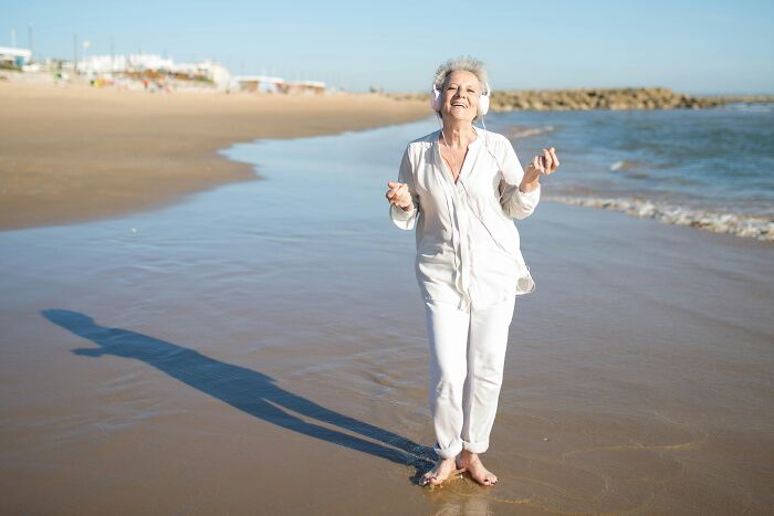 Senior woman enjoying a sunny day on the beach, exemplifying brilliant life hacks for happiness and well-being.